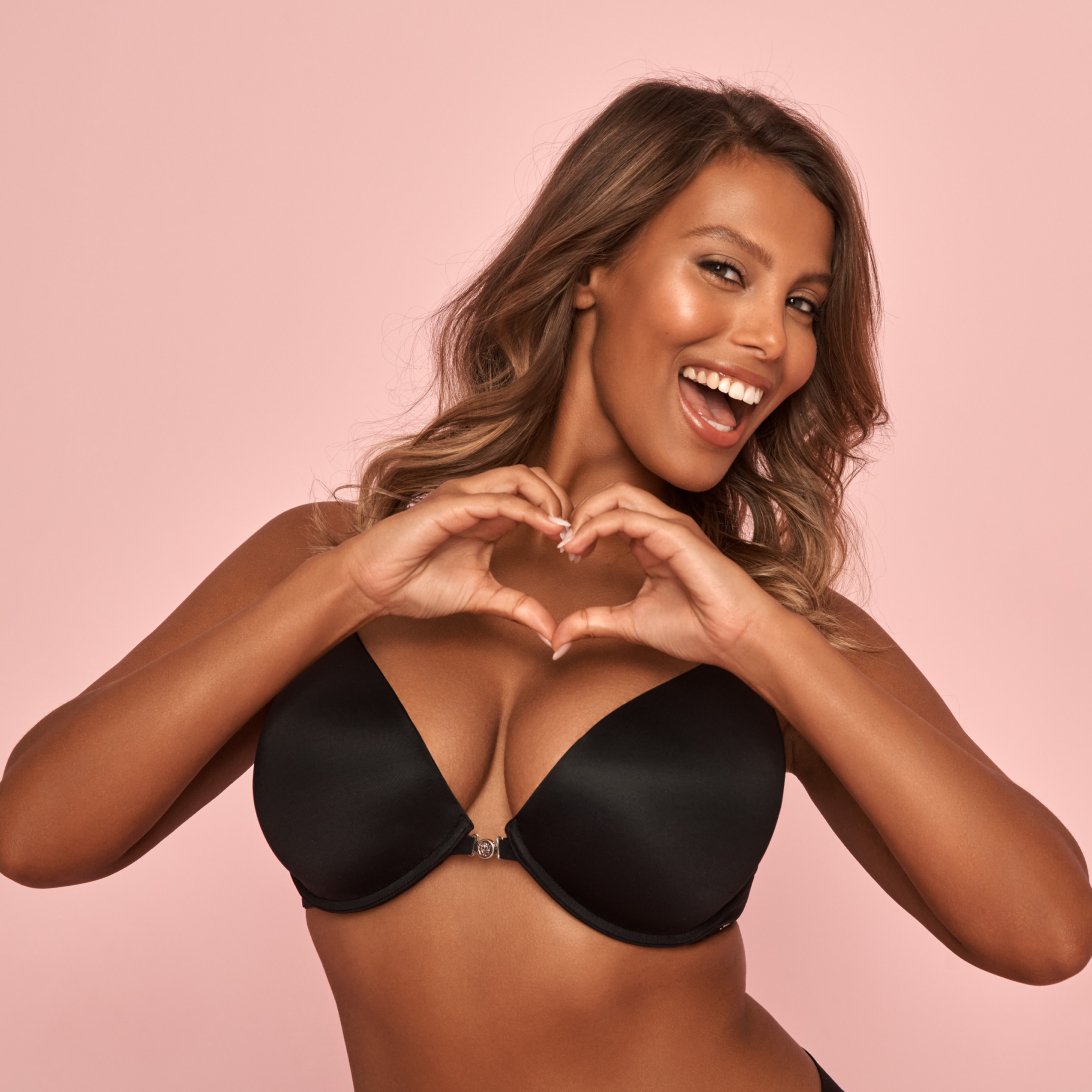 Model wearing a black bra, forming a heart shape with her hands.